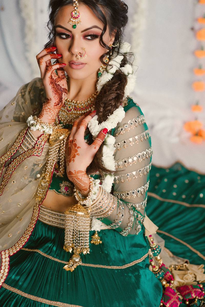 Woman in green dress sits with henna tattoos on wrist and arms