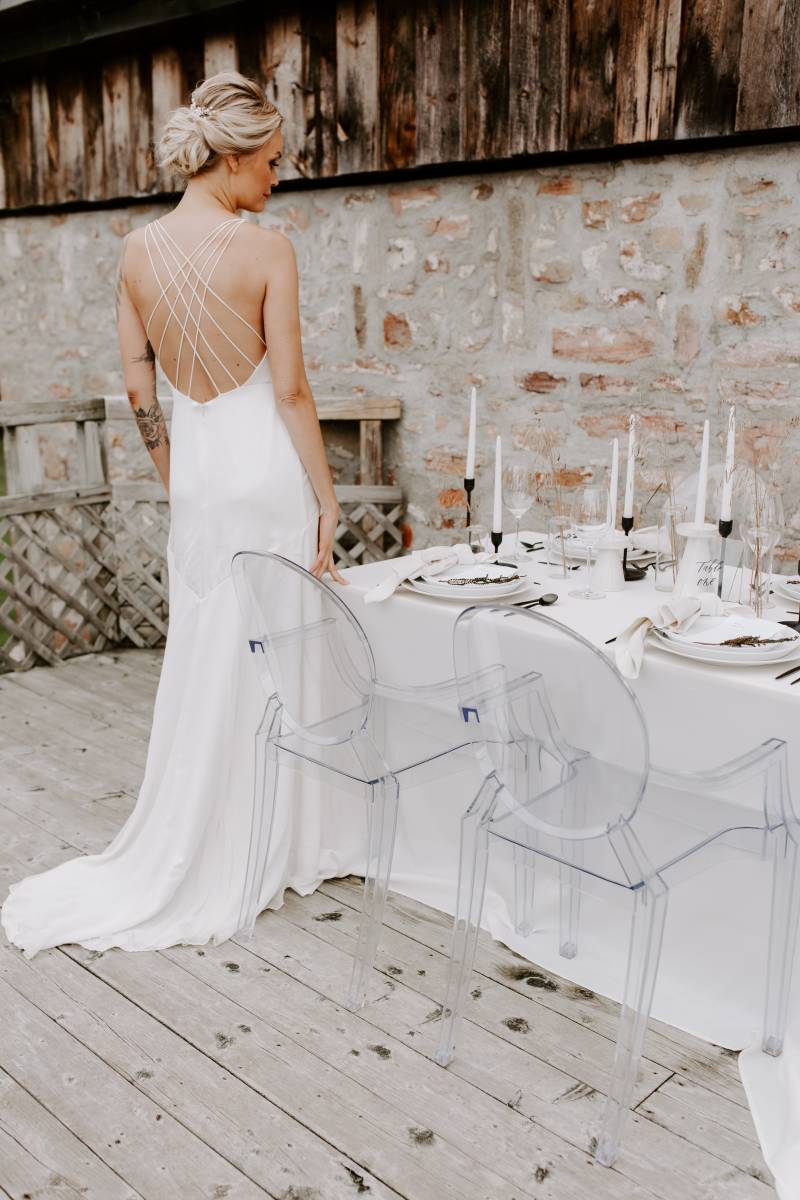 Woman in white backless dress facing away at white minimalist table 