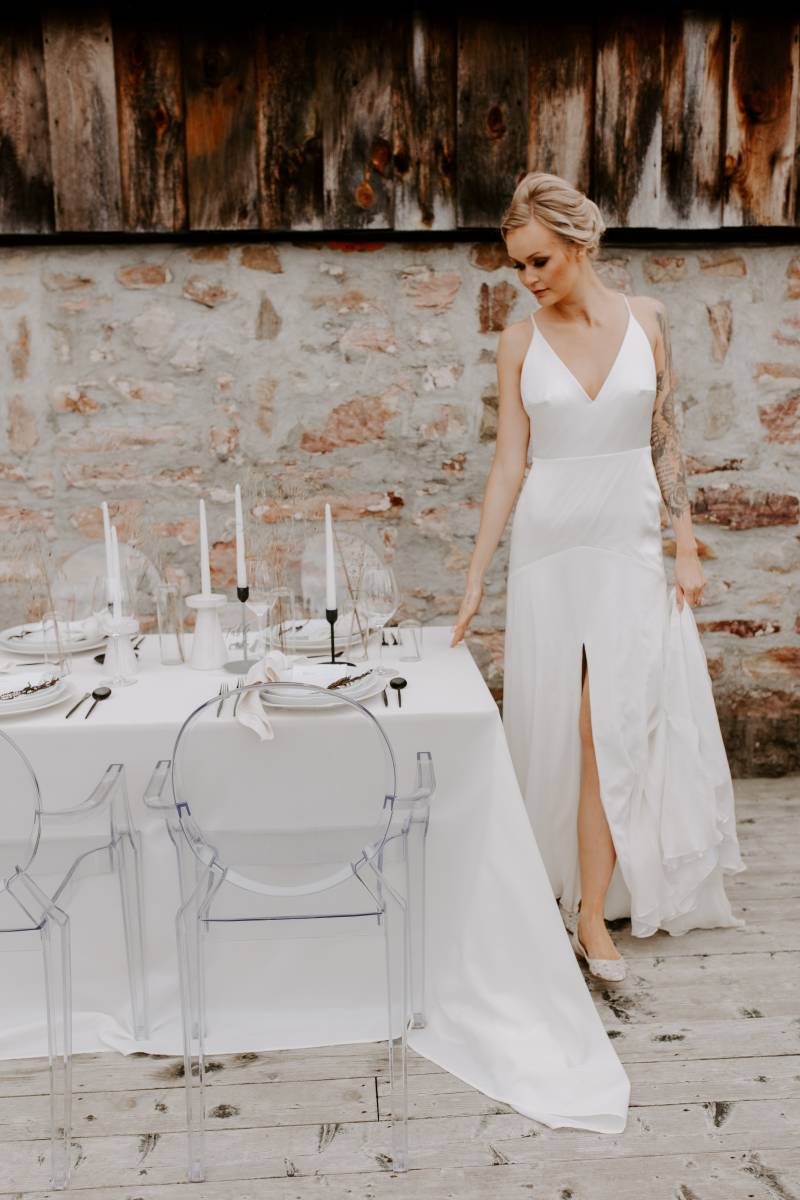 Woman wearing white slit skirt dress beside white table scape with black accents