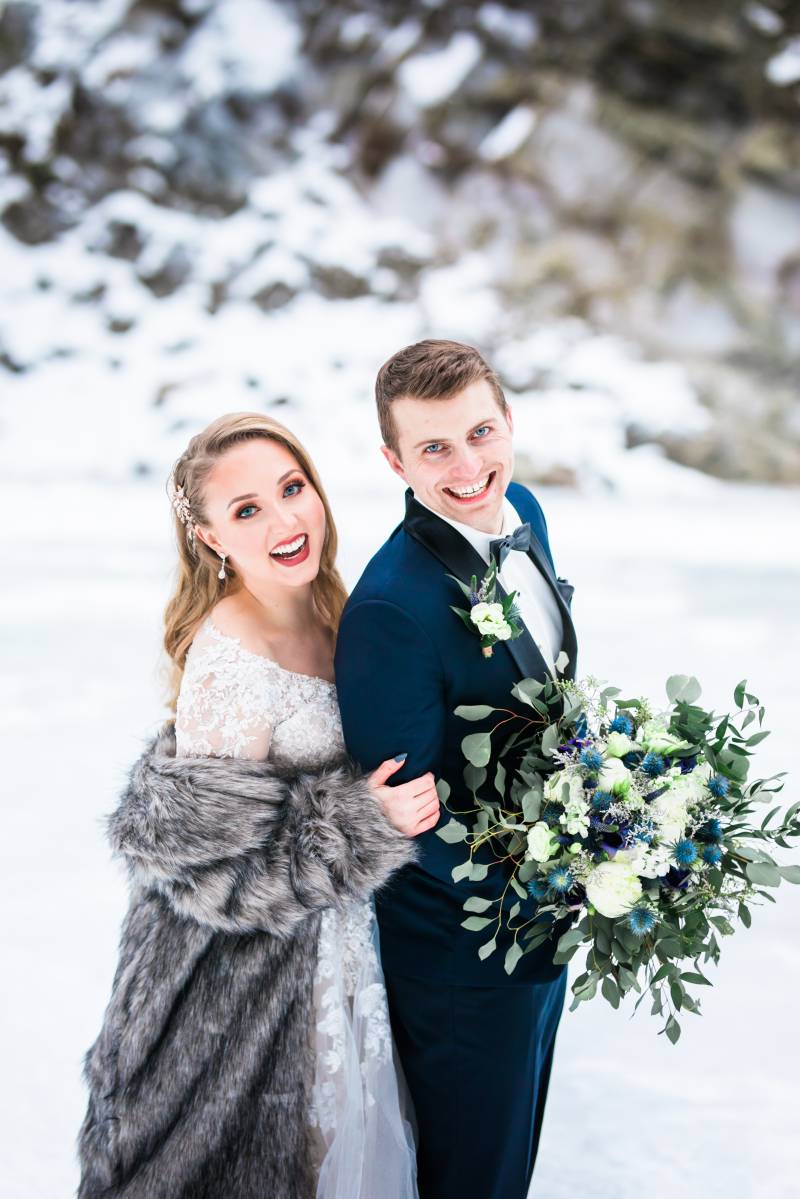 Bride and groom lean forward smiling on frozen tundra 