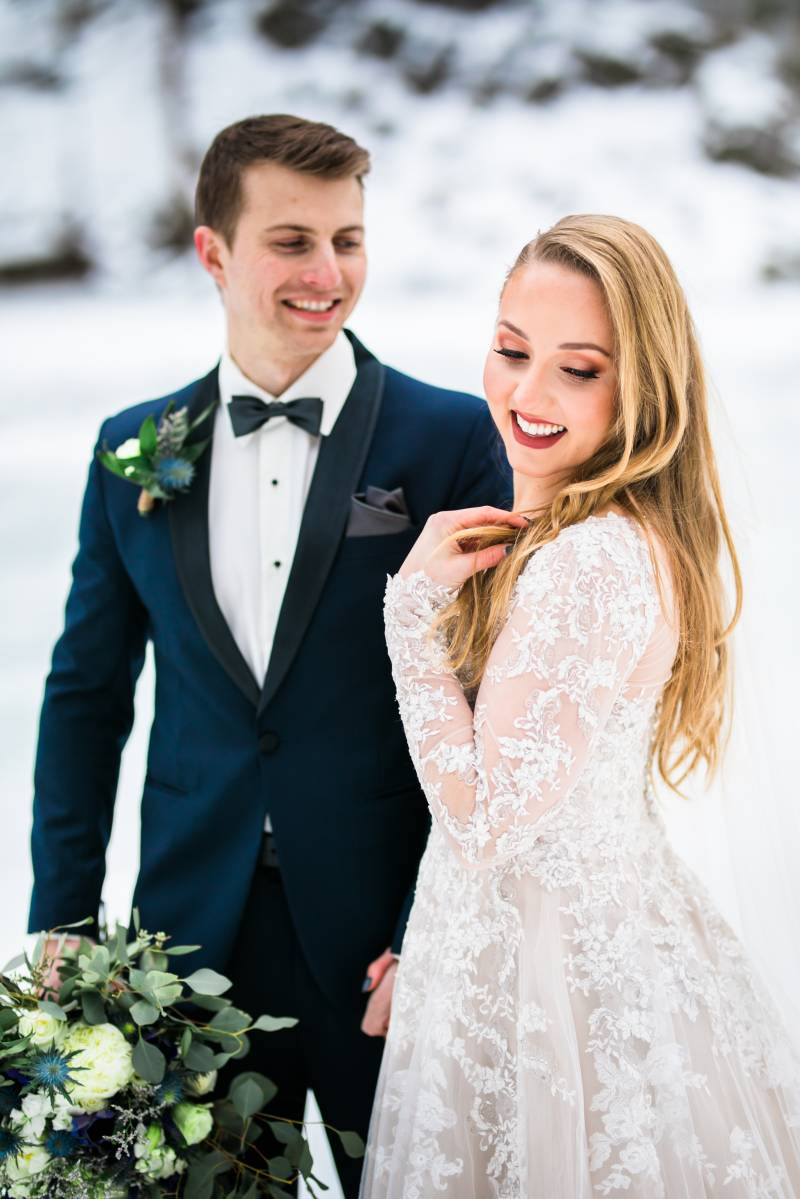 Bride and groom smile looking over shoulder walking on frozen tundra 