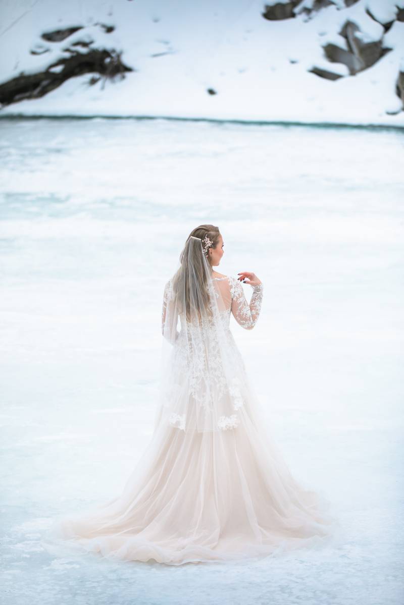 Bride in white lace dress walks on snowy tundra