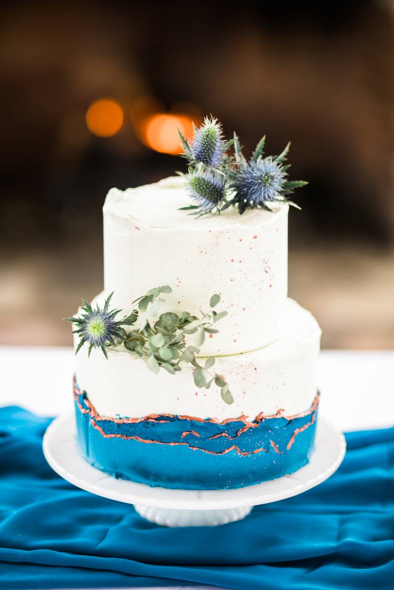 Wedding cake with cobalt base and white and orange upper sections 