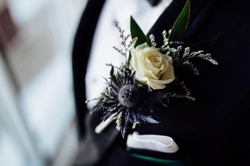 Purple and white boutonniere on black suit 
