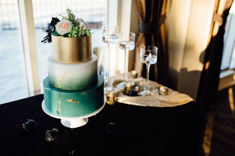 Teal white and gold wedding cake on  black table with gold table runner 