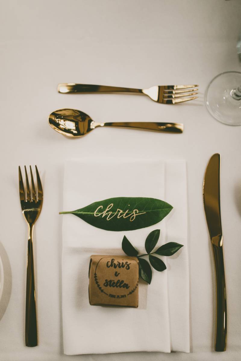 Place setting flat lay with gold cutlery and leaves with gold lettering  