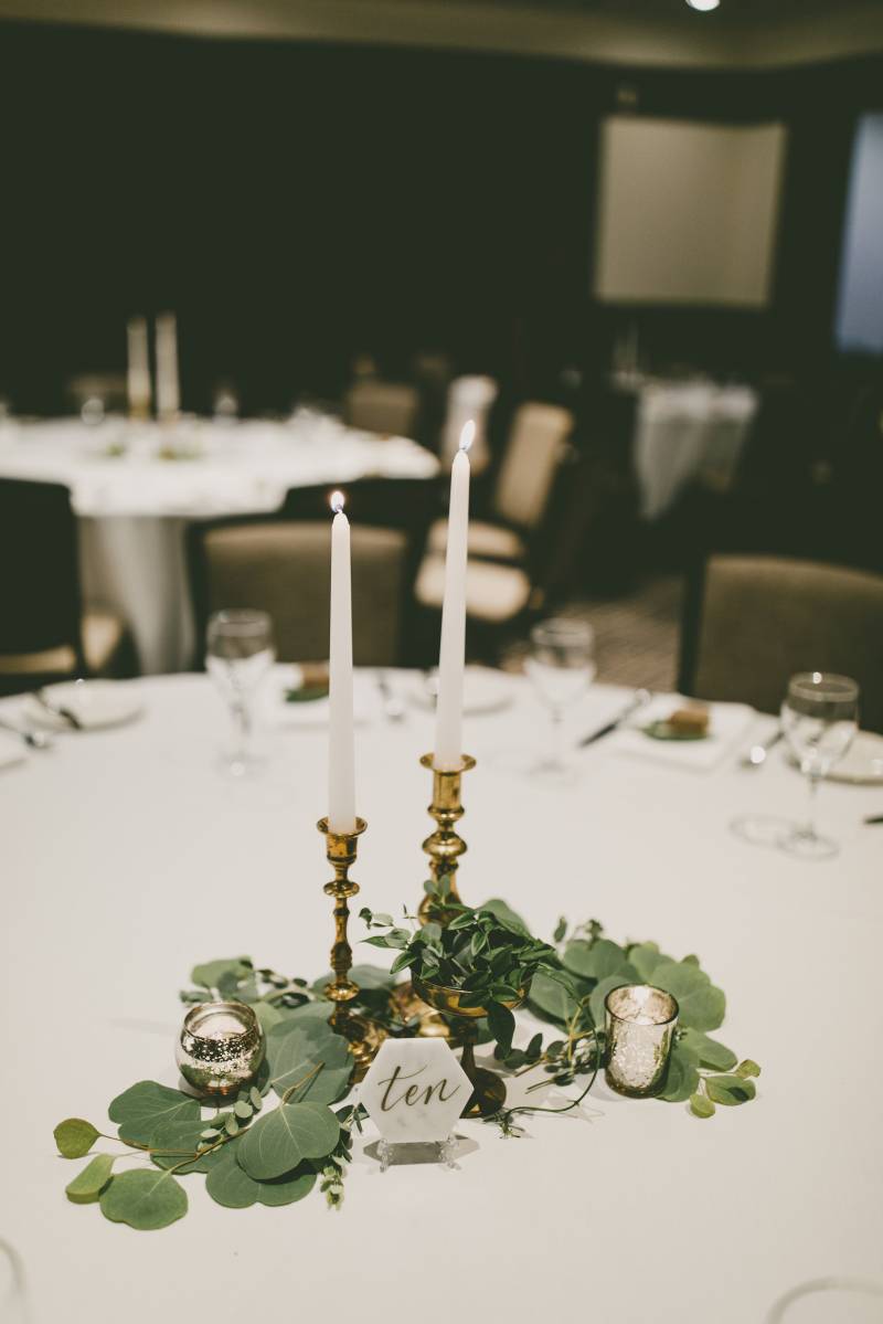 white round table with gold candlesticks and greenery in middle 