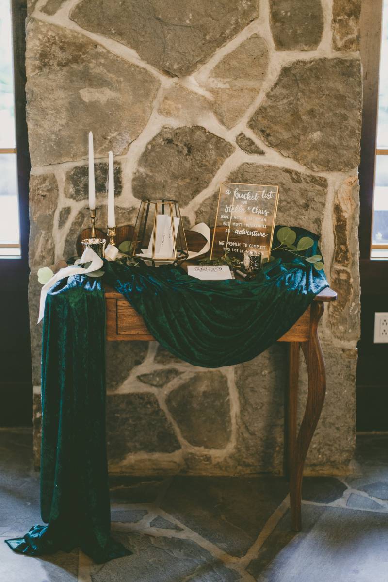 Table with dark green fabric and candlesticks against stone wall  