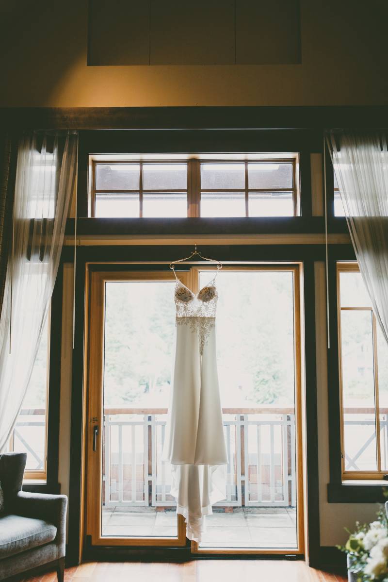 White wedding dress hanging in front of glass doorframe 