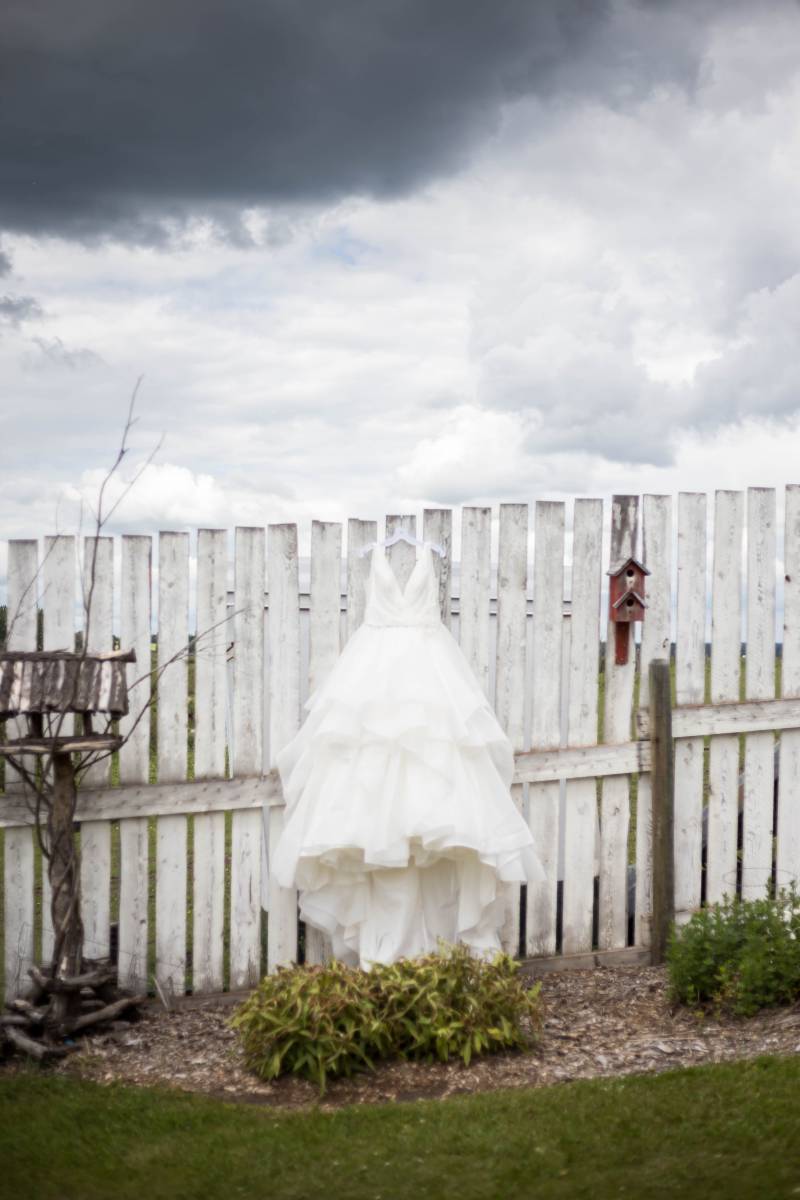 White dress hanging on white wooden fence 