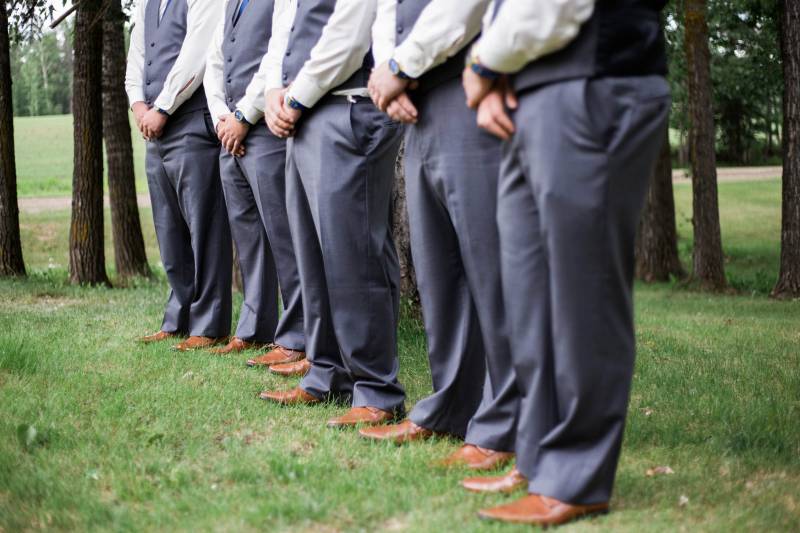 Groomsmen and groom stand hands crossed in line wearing chocolate brown shoes