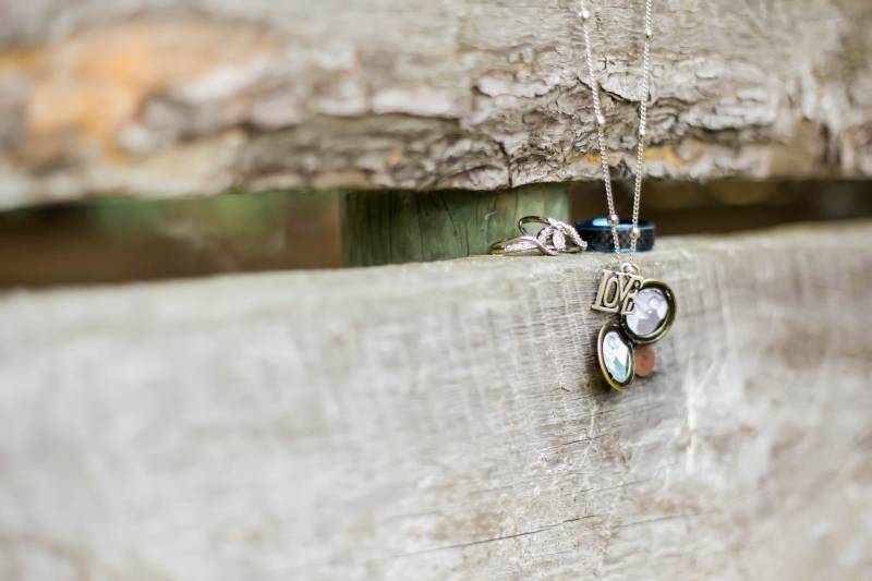 Love necklace and locket hanging on wooden fence