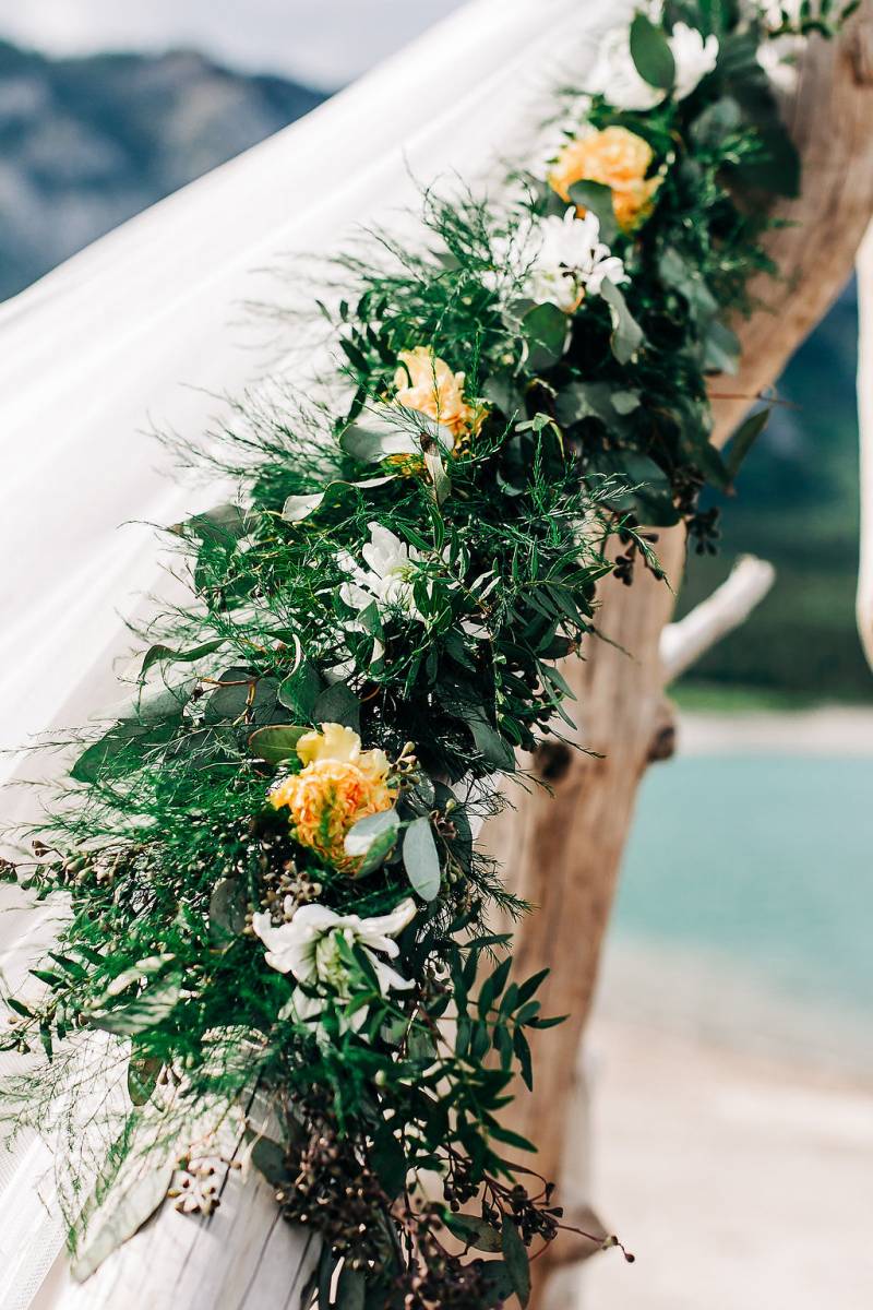 Greenery with yellow and white flowers on driftwood