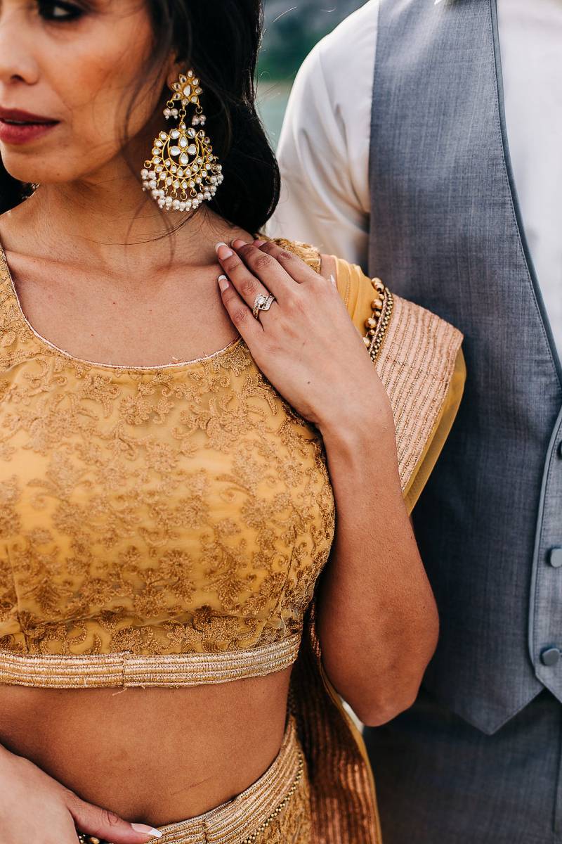 Woman touches shoulder in yellow dress man in grey vest behind 