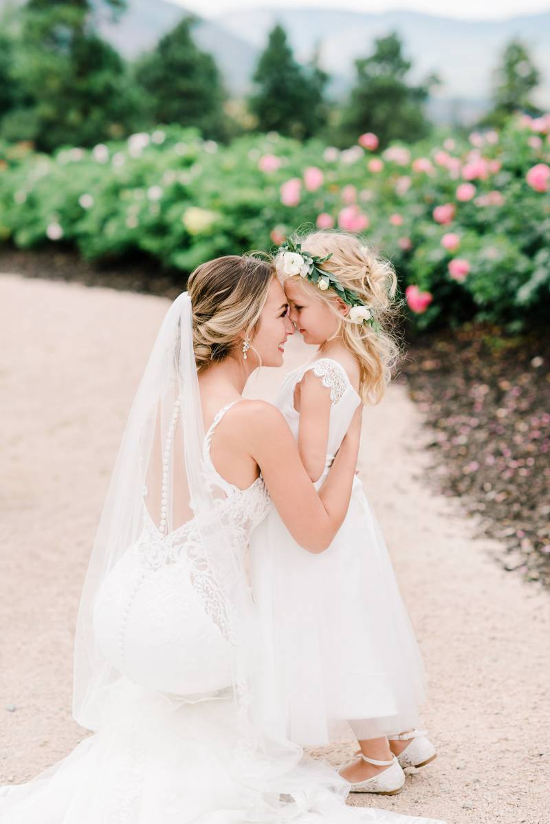 Bride smiling touching foreheads with child in flower crown 