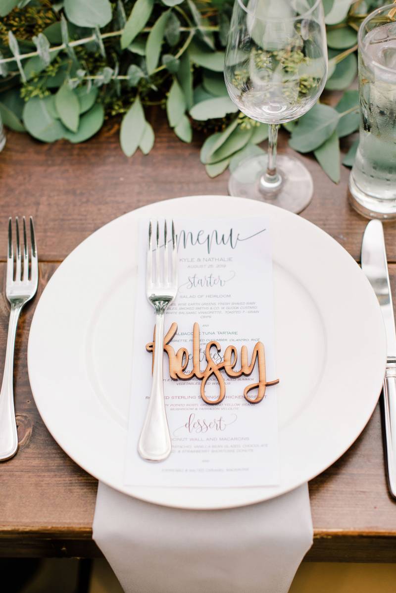 Table setting with gold seating names on wooden table 
