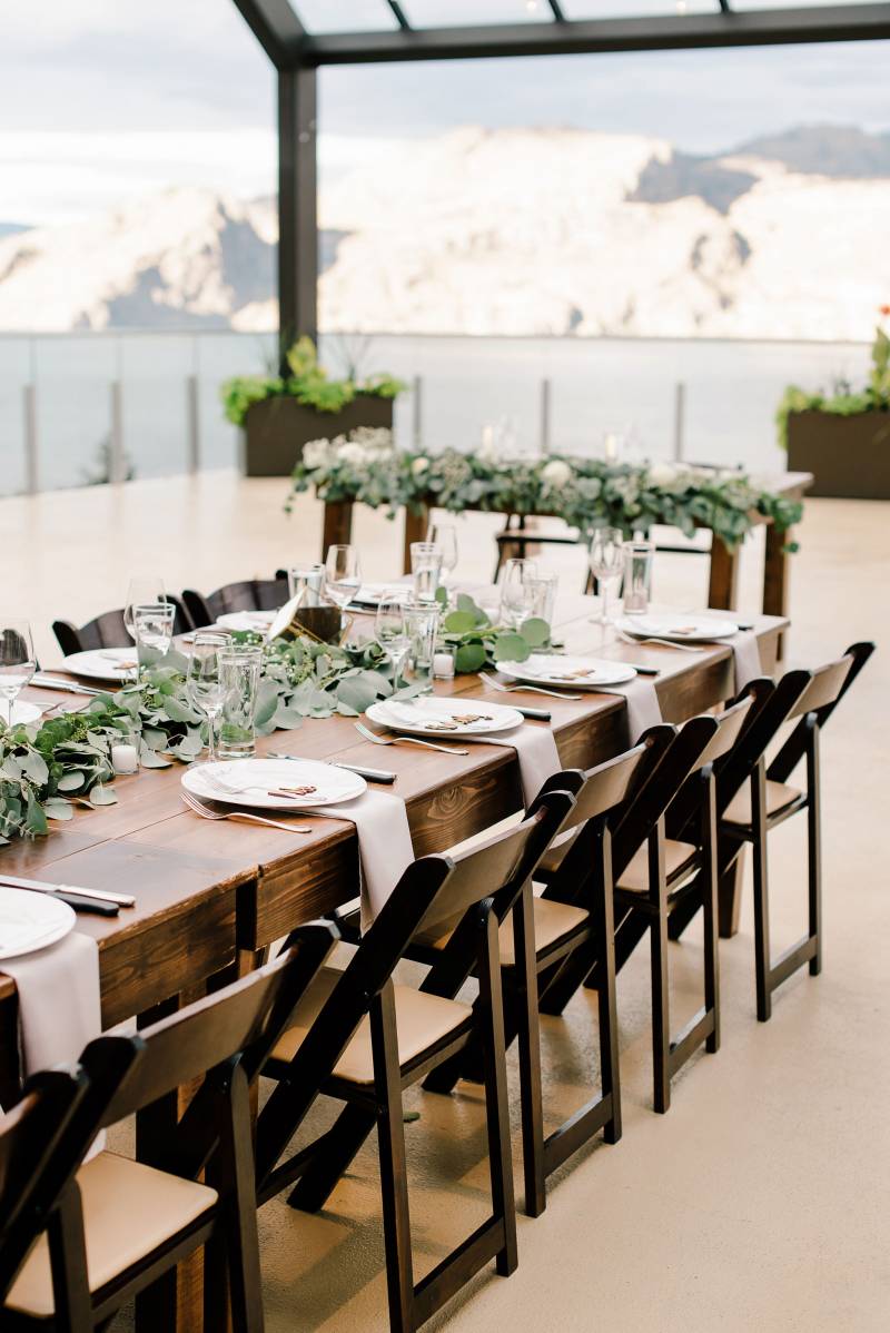 Outdoor terrace wedding reception table with dark wood chairs and long wood table 