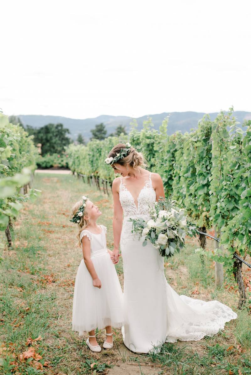 Bride and child walking in white flower crowns in peach field