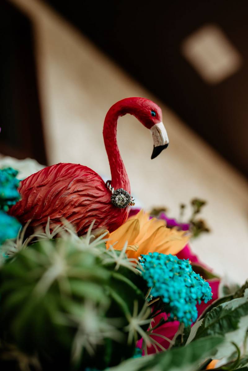 Red flamingo ornament with aqua and yellow flowers around it 