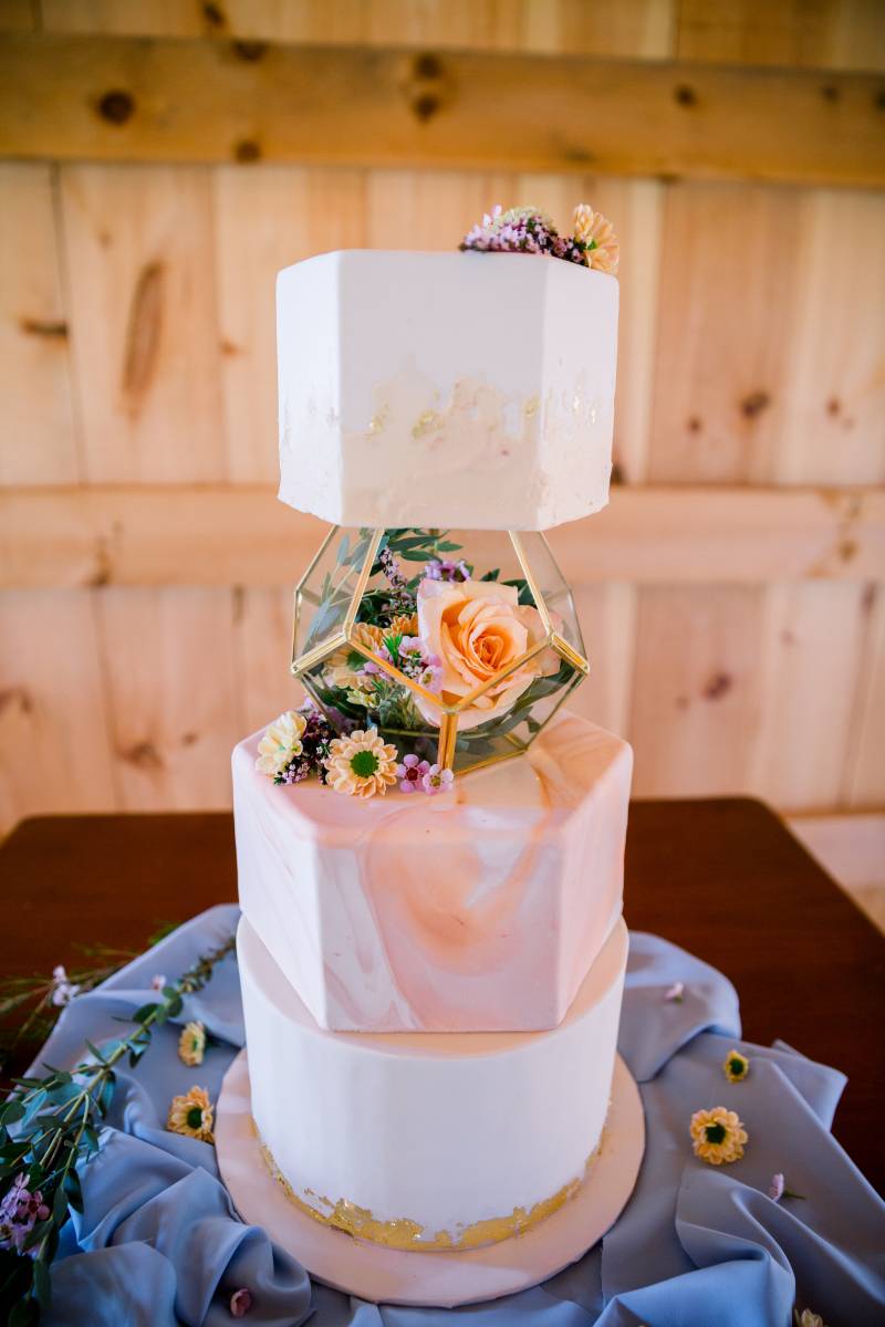 Three tiered Geometric wedding cake on blue fabric 