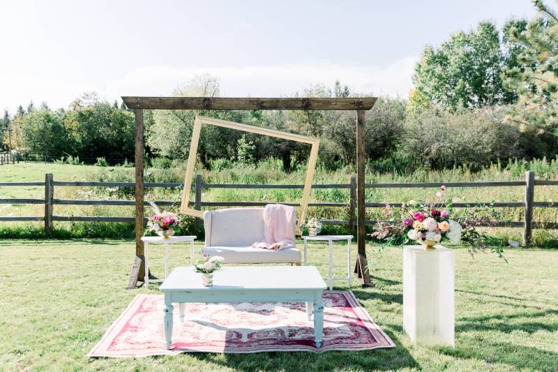 Wedding arch with lopsided frame behind white sofa and table on rug