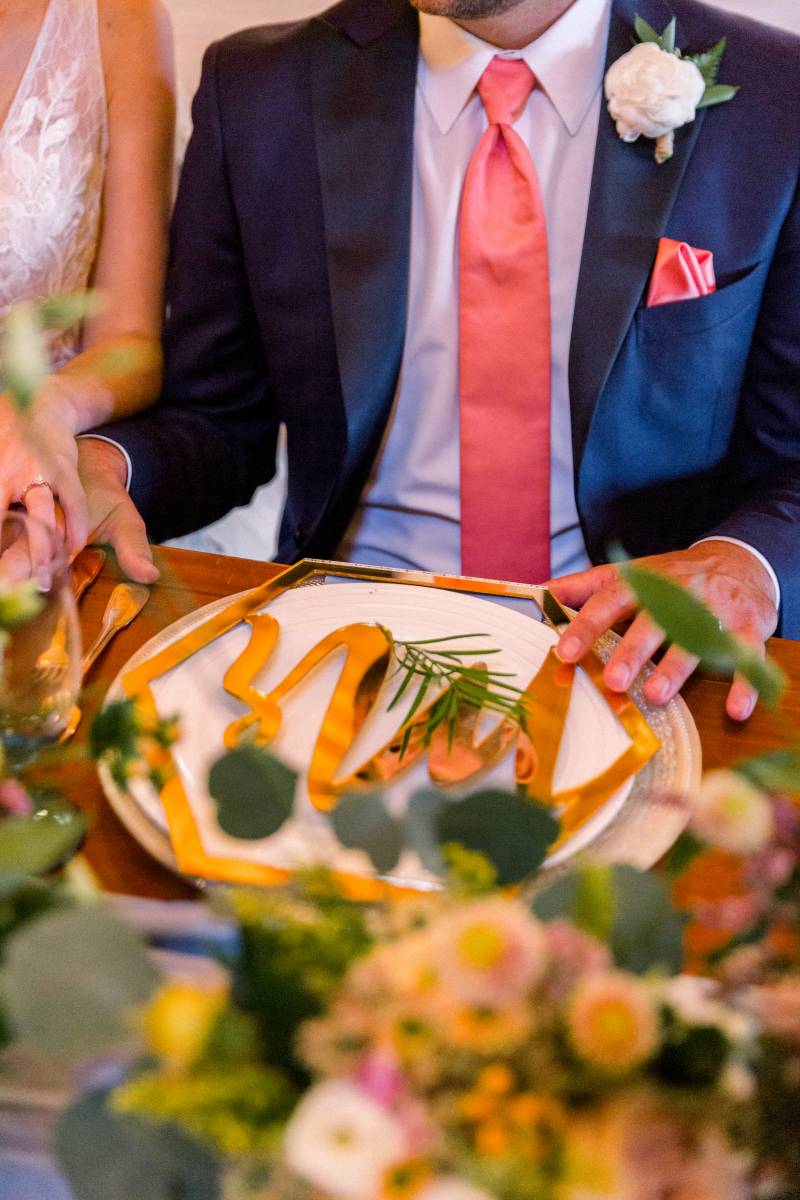 Groom sits in front of gold place setting and cutlery 