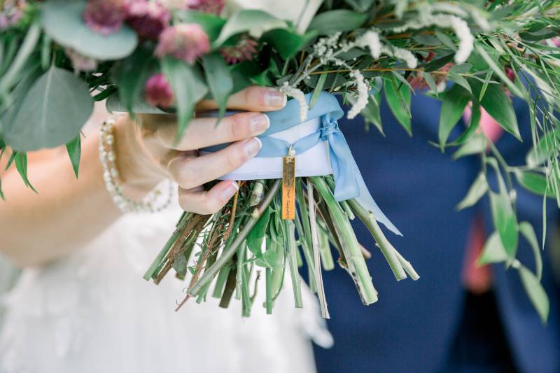 Bride holding bouquet with blue ribbon and gold pennant 