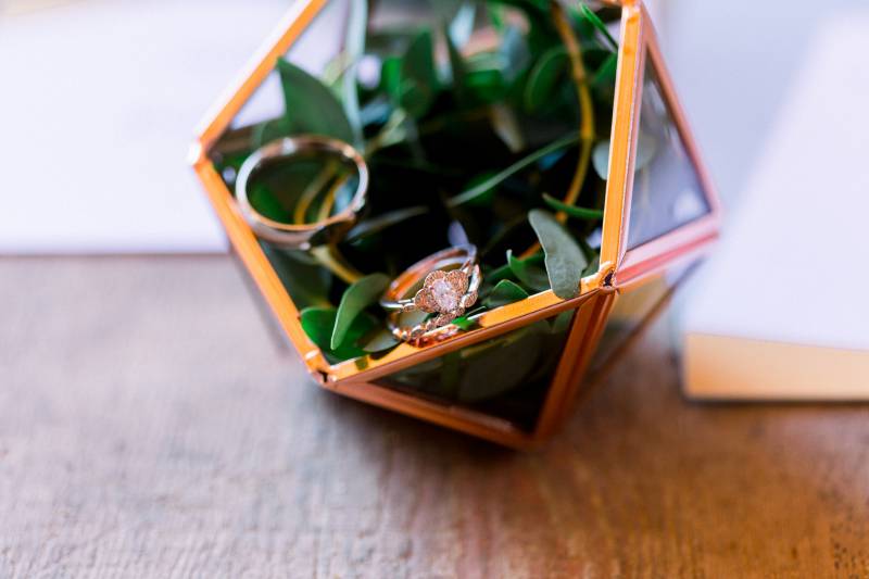 Gold geometric octagon with wedding rings and greenery inside  
