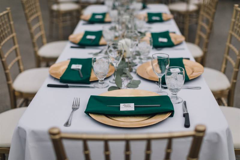 Gold chairs at white table and with gold plates and forest green accents 
