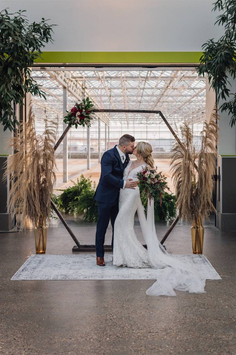 Man and woman kiss in front of geometric wedding arch 