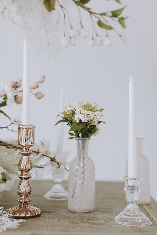 Blush flower vase with blush flowers in between two candlesticks 