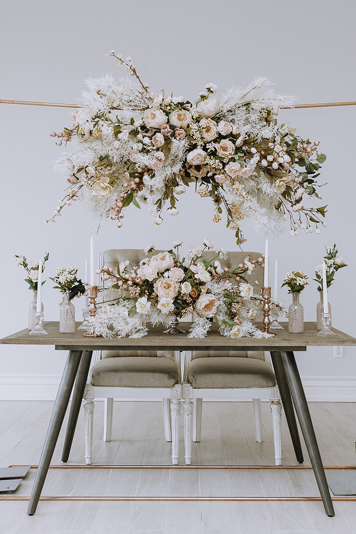Large hanging floral arrangement over small table with large blush centerpiece and candlesticks