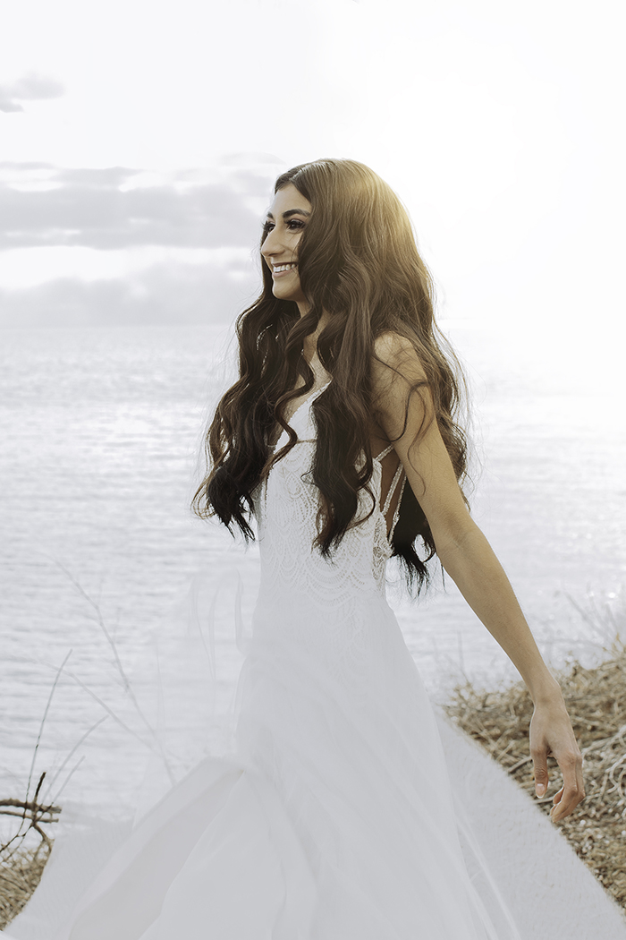 Woman in white dress smiling arms straight behind 