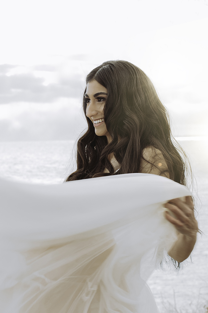 Woman in white dress holds up skirt smiling 
