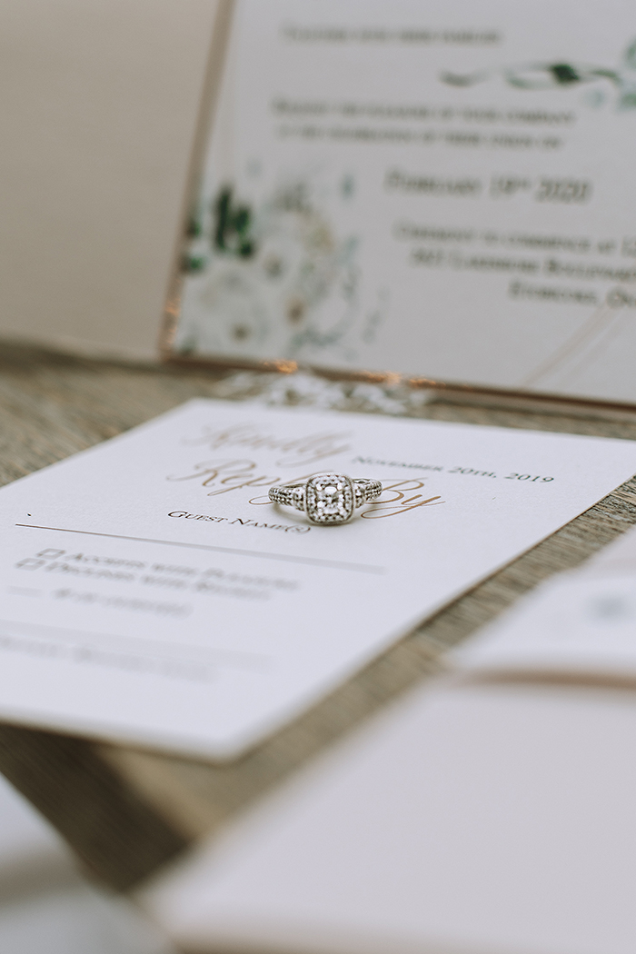 Wedding ring laying on top of wedding invitations