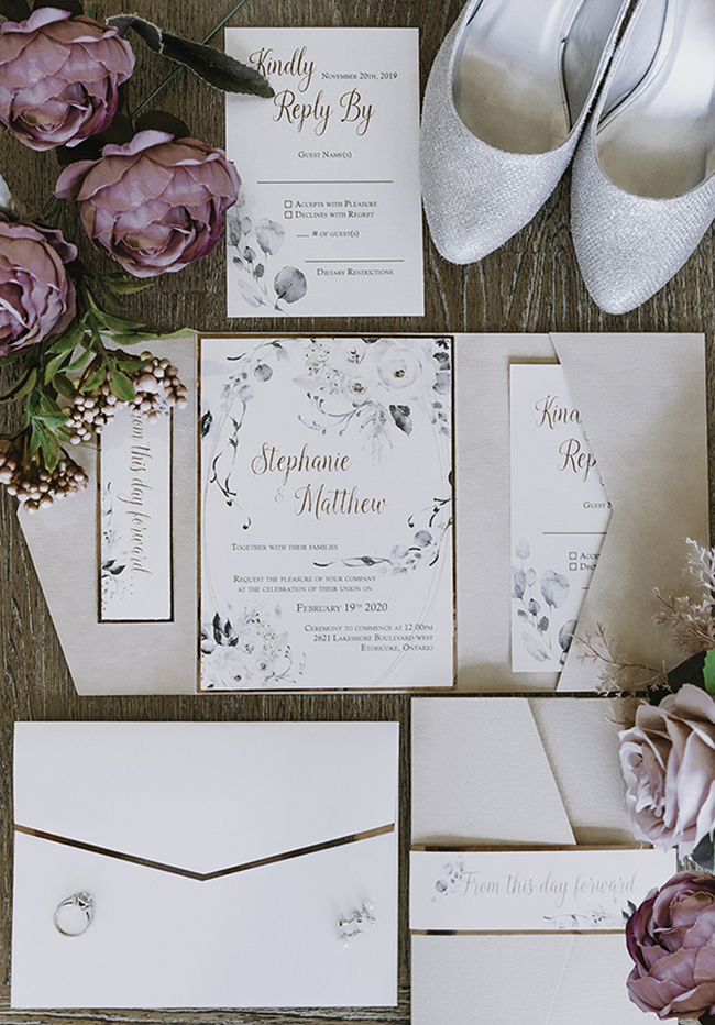 Wedding invitations flat lay with sparkling white heels in background and blush flowers 
