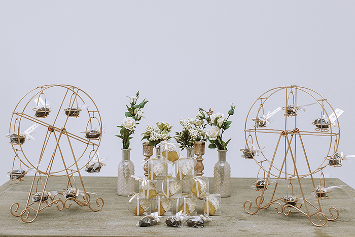 Miniature bronze Ferris wheels with wrapped chocolate in seats in between stacked treats 