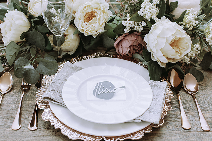 Large blush and white centerpiece in front of pink gold plate and cutlery 