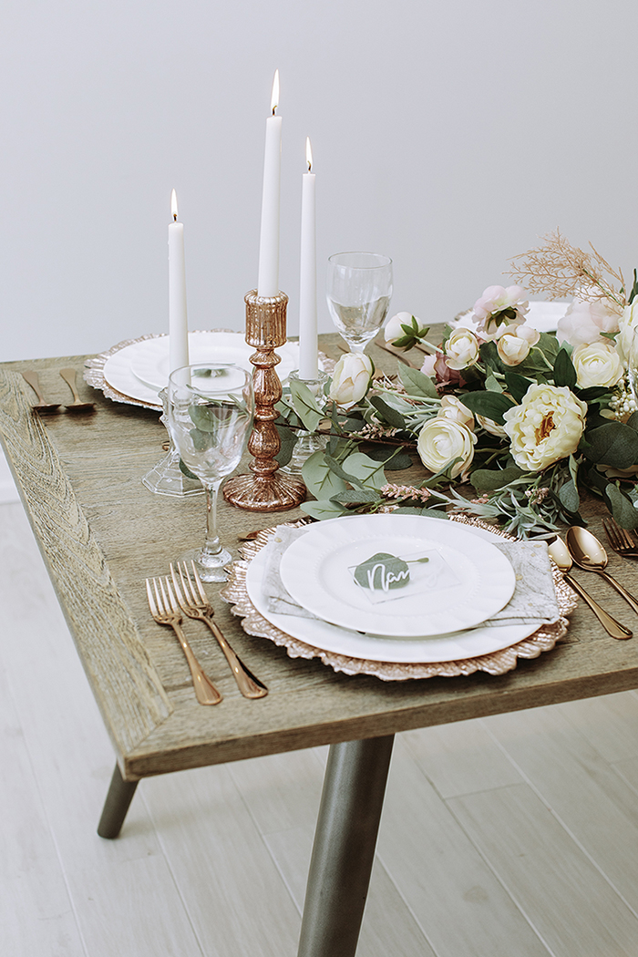 Large blush and white centerpiece in front of pink gold plate and cutlery 