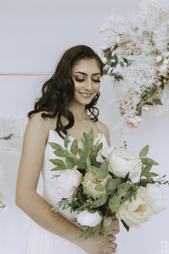 Woman smiling in white dress holding white bouquet 