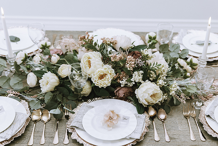 Large blush and white centerpiece in front of pink gold plate and cutlery 