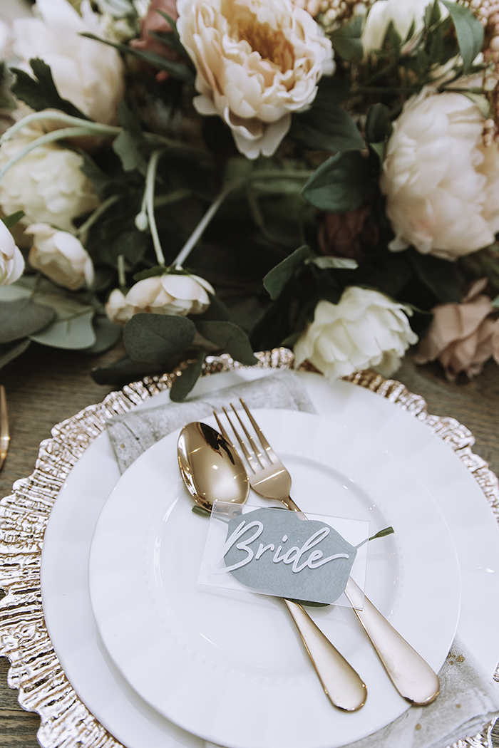 Clear glass Bride tag on top of blush gold cutlery on plate 