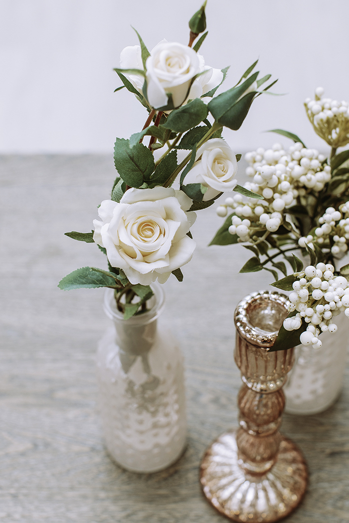 Pink gold and clear vases holding white flowers 