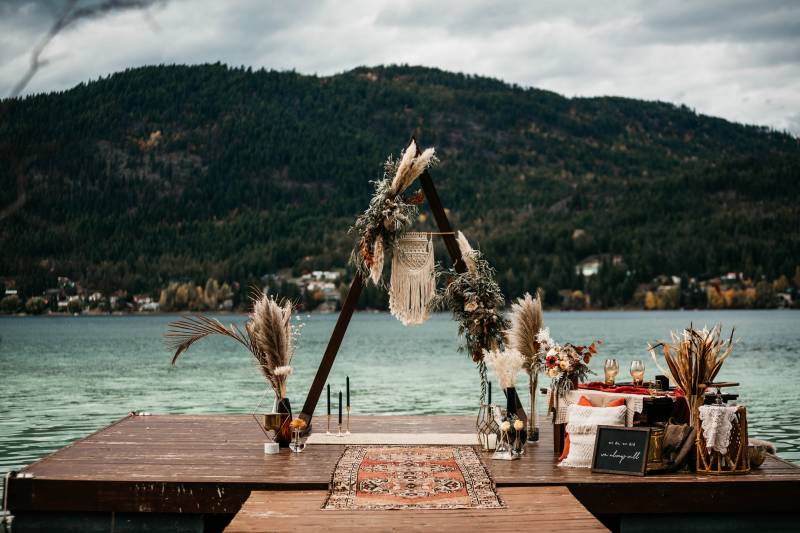 Triangular wedding arch with macramé and pampas grass accents at the end of dock facing lake