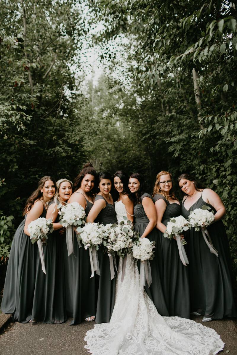 Bride standing in between bridesmaids smiling holding white bouquets 