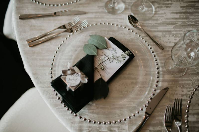 Place setting flat lay with clear plate and black napkin