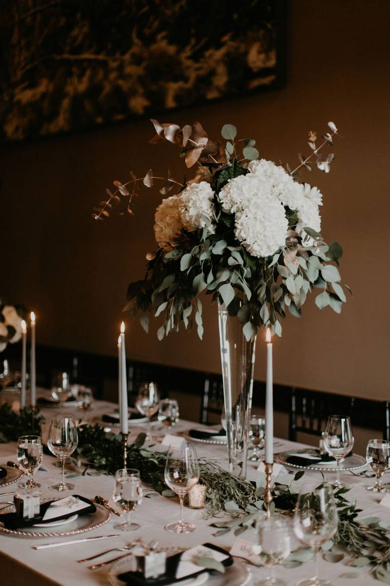 Large clear vase with white flowers over the top 