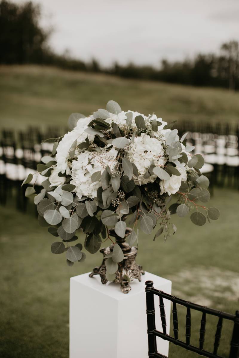 White pedestal with white floral bouquet on top 