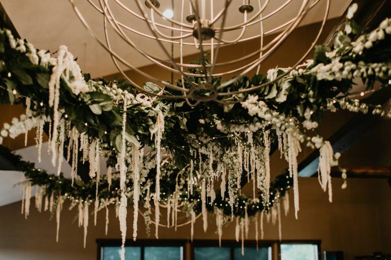 Large handing floral piece under chandelier  
