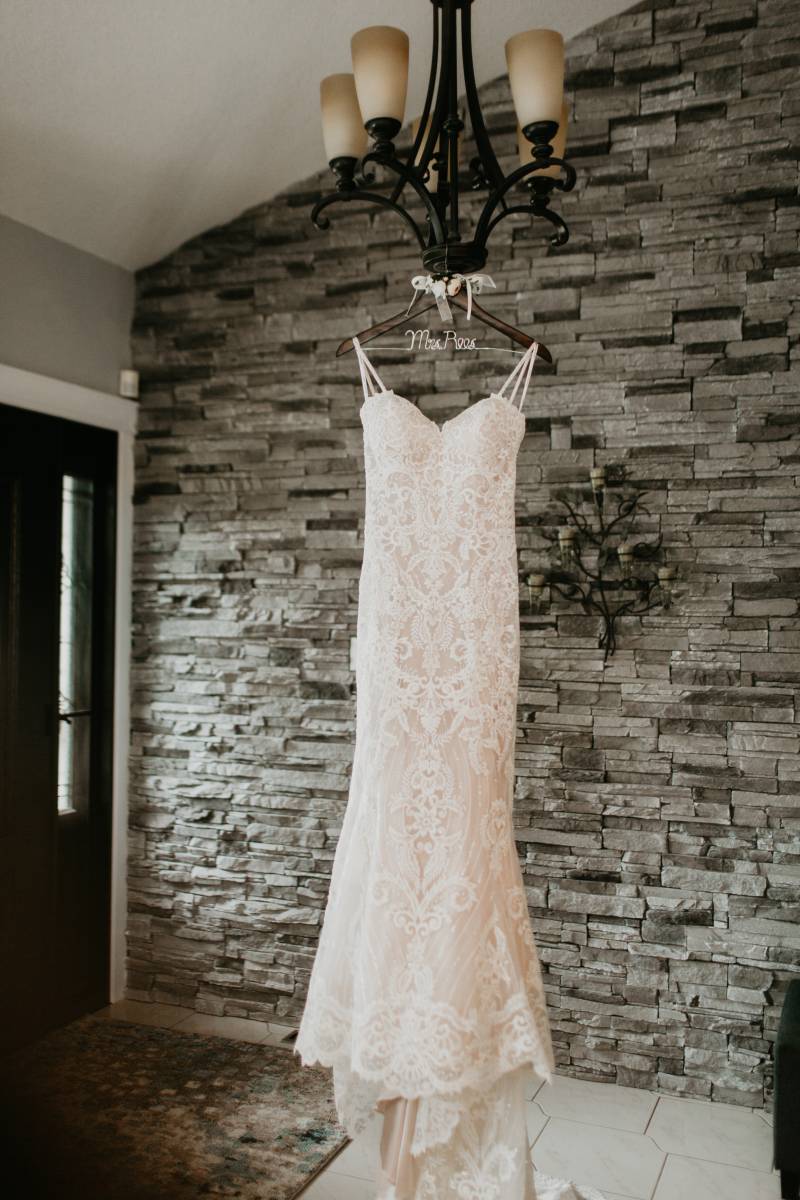 White lace wedding dress hanging from chandelier 